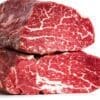 Two cuts of raw marbled beef stacked, showing white marbling on red meat, white background.