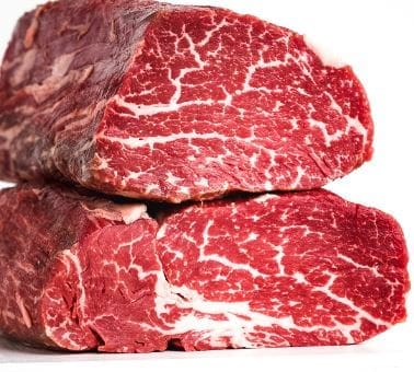 Two cuts of raw marbled beef stacked, showing white marbling on red meat, white background.
