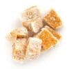Orange confection cubes with powdered sugar on white background.