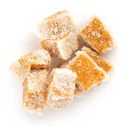 Orange confection cubes with powdered sugar on white background.