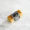 Small cylindrical block of Black Truffle Rebel Cheddar cheese, sealed, on a marble surface.
