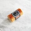 Cylindrical paprika cheese on plain marble background.