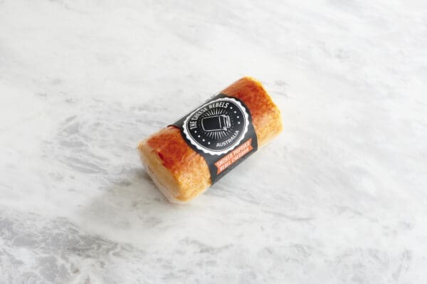 Cylindrical paprika cheese on plain marble background.