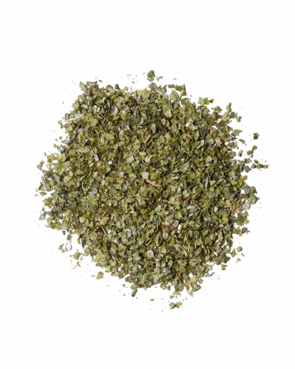 Dried, crushed green leaves on a white background, used as seasoning or herb in cooking.