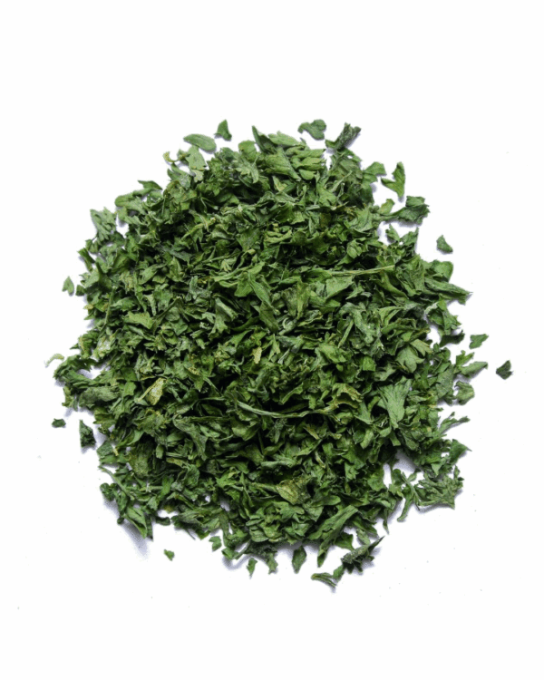Pile of finely chopped green dried herbs on a white background.