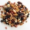 Assorted nuts and dried fruits on a white surface, including almonds, walnuts, and raisins.