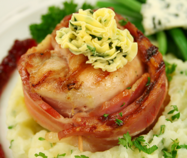 Chicken wrapped in bacon with herb butter on mashed potatoes, green beans, cheese, cranberry.