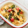 Baked vegetable gratin with broccoli, peppers, zucchini, cheese topping on light surface.