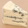 Wedge of blue cheese with creamy color and blue veining, soft and crumbly texture.