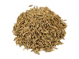 A pile of brown cumin seeds on a white background, elongated with a ridged texture.