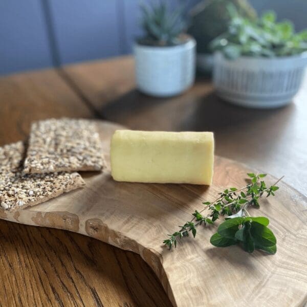 Butter, crispbread, and thyme on a wooden board; potted plants in the background.