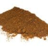 Pile of coarse ground brown spices on a white background with visible particles.