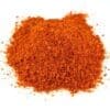 Small pile of coarse red-orange ground spice on white background.