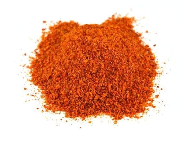 Small pile of coarse red-orange ground spice on white background.