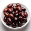 Bowl of dark reddish-brown glossy olives on a white background.
