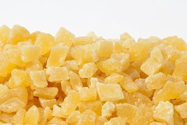 Small, cubed, dried pineapple pieces with sugary coating, light yellow color.