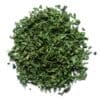 Pile of finely chopped green dried herbs on a white background.