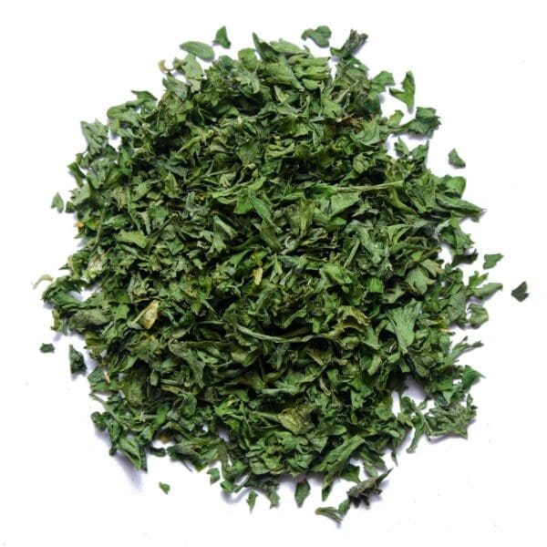 Pile of finely chopped green dried herbs on a white background.