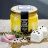 Jar of 320g goat cheese marinated in olive oil with garlic, thyme, and peppercorns.
