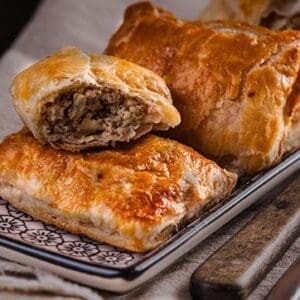 Golden brown puff pastries with savory mushroom filling on a decorative plate.