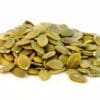 Close-up of green pumpkin seeds (pepitas) on a white background, flat and glossy.