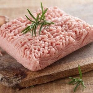 Ground turkey on a wooden board with rosemary and garlic in view.