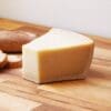 Wedge of hard cheese with crusty bread on wooden surface.