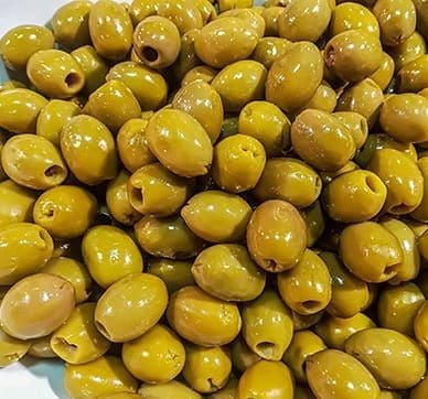 Green olives with pits, shiny from marination, displayed in a pile.