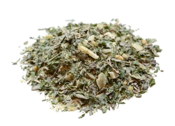 Close-up of mixed dried herbs and spices with green leaves on a white background.