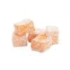 Orange confection cubes with powdered sugar on white background.