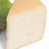 Wedge of pale cheese with textured rind on green lettuce background.