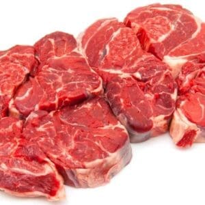 Raw beef steaks in a line on white surface, showing marbled textures, various red shades.