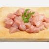 Raw cubed chicken breast on a wooden board with parsley garnish.