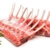 Two racks of raw lamb ribs with fresh rosemary sprigs on a white surface.