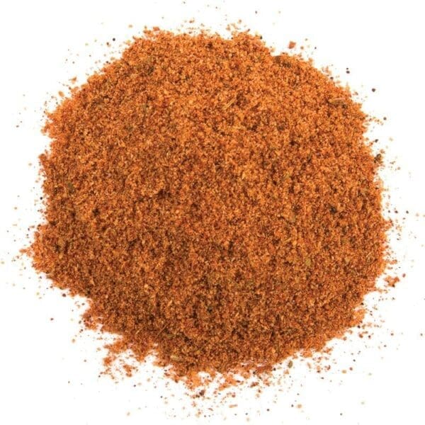 Pile of reddish-brown spice mix on a white background, coarse and granular texture.