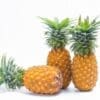 Three ripe pineapples on white background, two upright, one lying, showing textured skin.