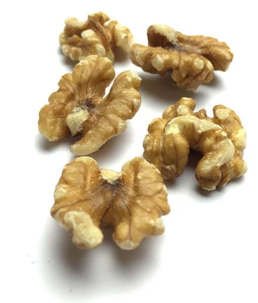 Shelled walnut halves on white surface, showing ridged and uneven textures.
