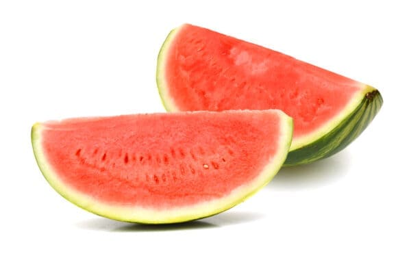 Whole watermelon and slices on white surface, green exterior, red interior with seeds.