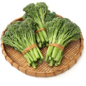Woven bamboo tray with fresh broccolini bundles, dark green stalks and florets secured with bands.