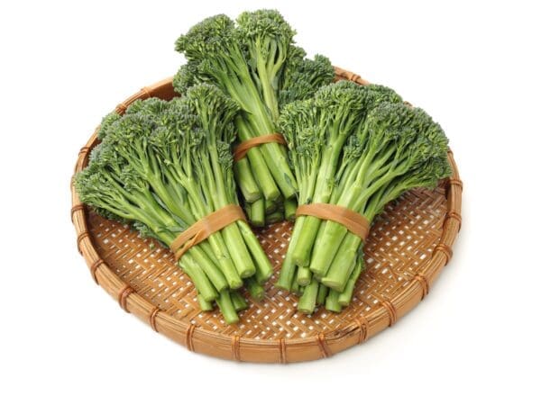 Woven bamboo tray with fresh broccolini bundles, dark green stalks and florets secured with bands.