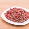 Plate with minced meat and vegetables on wooden table