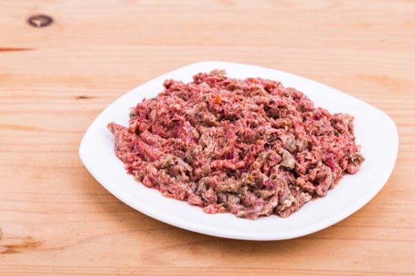 Plate with minced meat and vegetables on wooden table