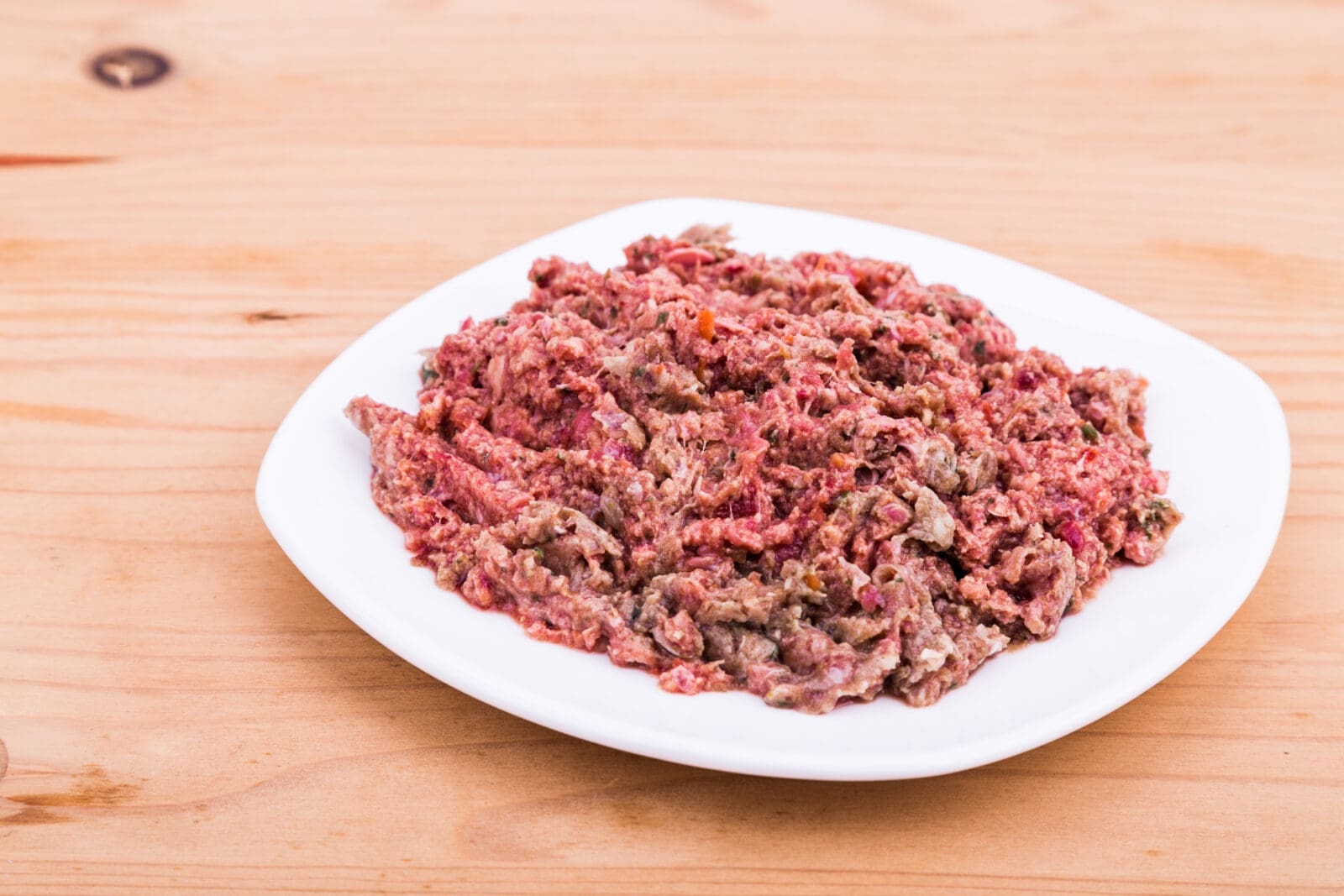 Plate with minced meat and vegetables on wooden table