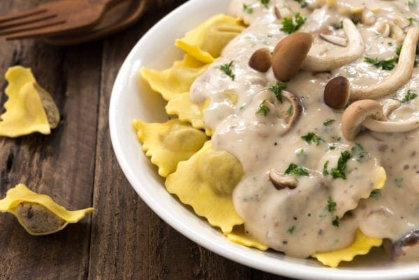 Plate,Of,Ravioli,With,Cream,Sauce,And,Mushroom,On,Wood