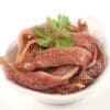 Small white bowl of anchovy fillets garnished with fresh parsley.