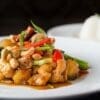 Colorful stir-fried vegetables with cashews on a plate, white rice in the background.