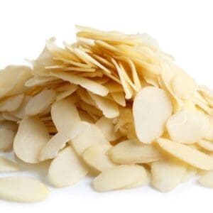Thinly sliced almonds piled on a white surface, showing creamy color and smooth texture.