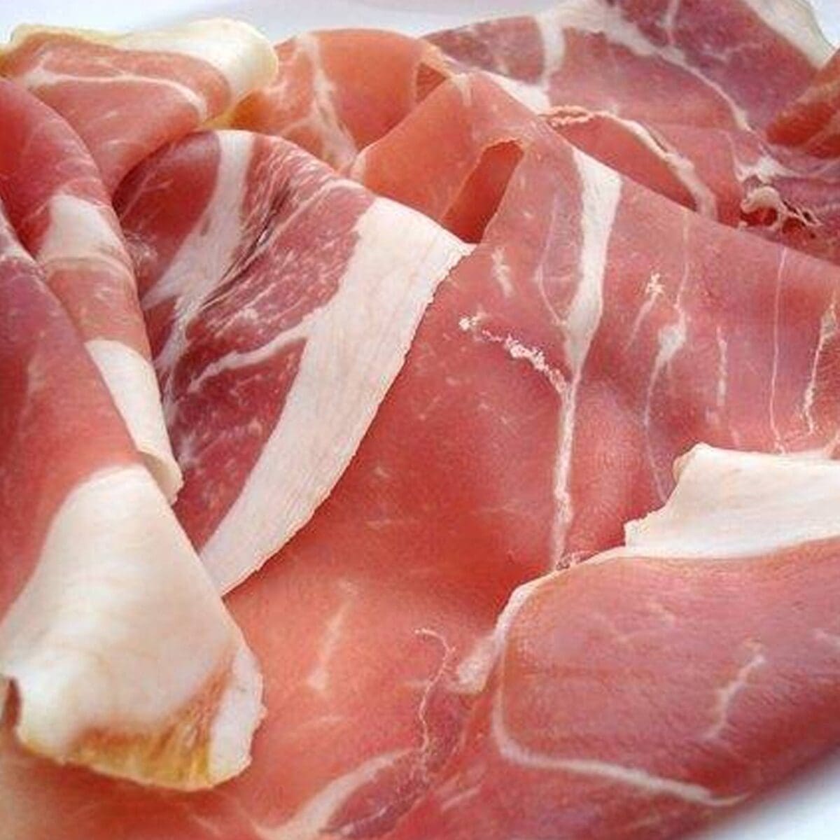 Thinly sliced prosciutto with marbling in pink and white tones.