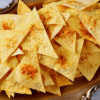 Triangular tortilla chips with spices on a decorative platter.