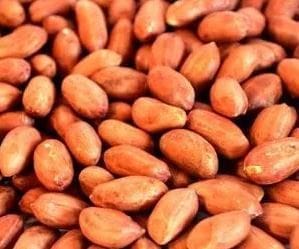 Close-up of unshelled peanuts with reddish-brown shells in a pile.